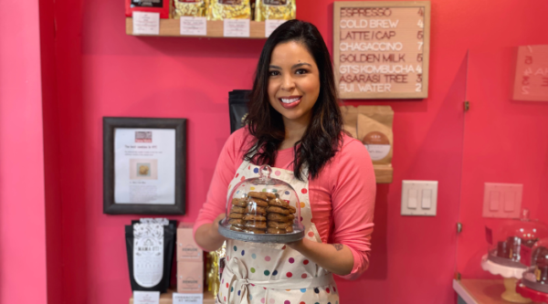Elisa Lyew, propietaria de Elisa's Love Bites en Nueva York, sonríe mientras sostiene una bandeja de galletas en su pastelería.
