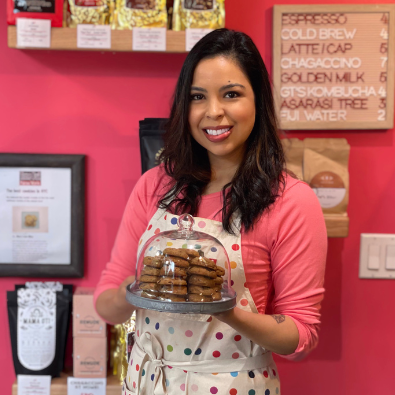 Elisa Lyew, propietaria de Elisa's Love Bites en Nueva York, sonríe mientras sostiene una bandeja de galletas en su pastelería.