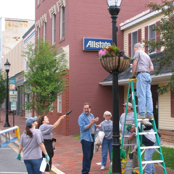 Photo showing a group of volunteers hanging planters in a downtown scene.