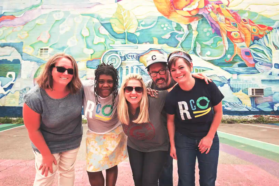 Covington, Kentucky staff members stand in front of a mural.