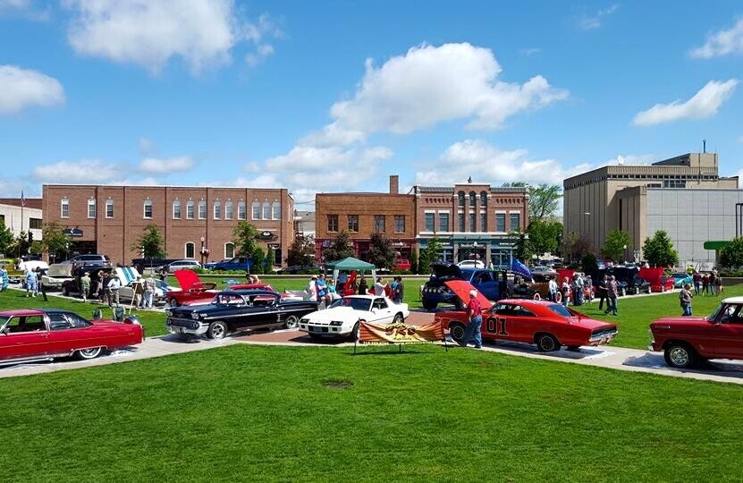 Classic cars are parked in a central square.