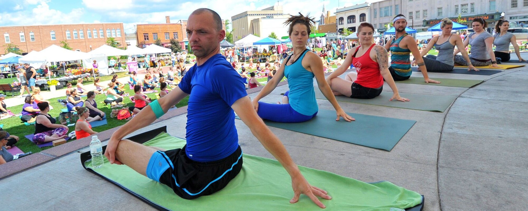 Los instructores de yoga dirigen a un gran grupo de personas que se reúnen en una plaza central.