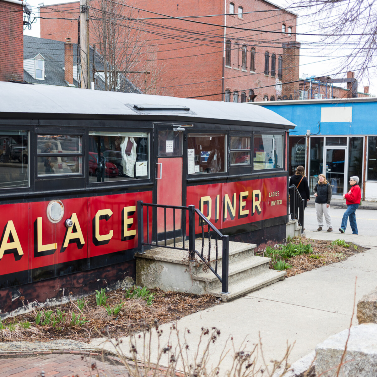 People stand outside an old railroad car that is home to a diner.
