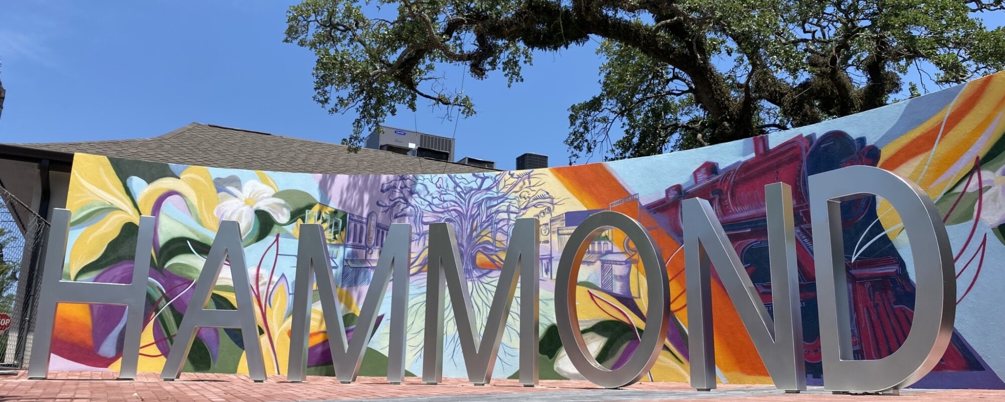 Unas letras independientes deletrean "HAMMOND" delante de una pared curva decorada con un mural de vivos colores.