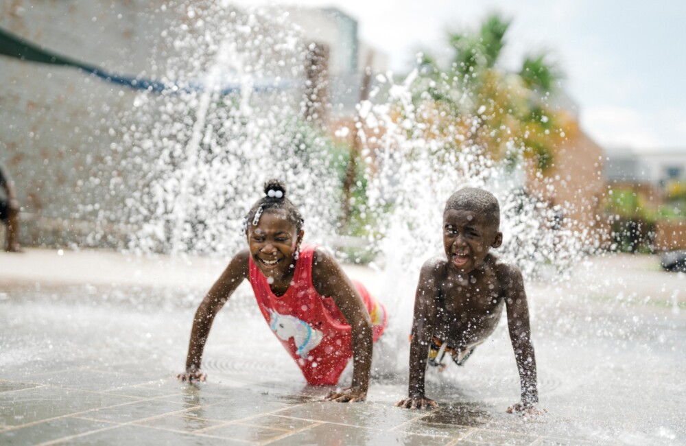 Dos niños pequeños juegan alegremente en una fuente de agua.