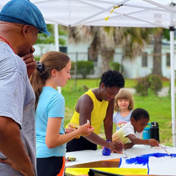 Adults and children create art at an outdoor event.