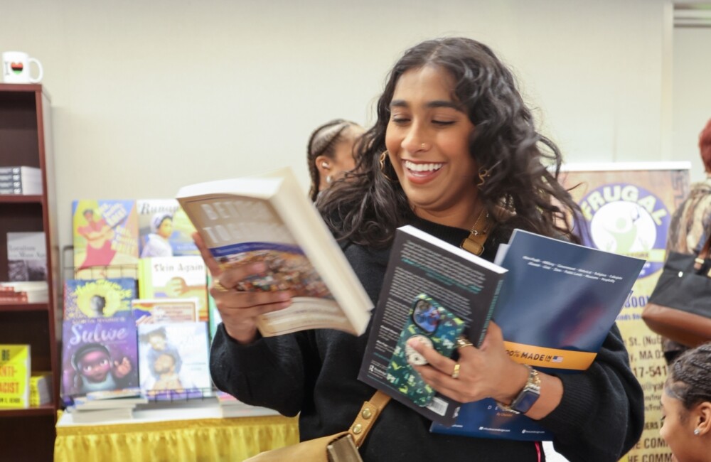 Una mujer sonríe mientras selecciona y hojea libros en una librería pop-up.