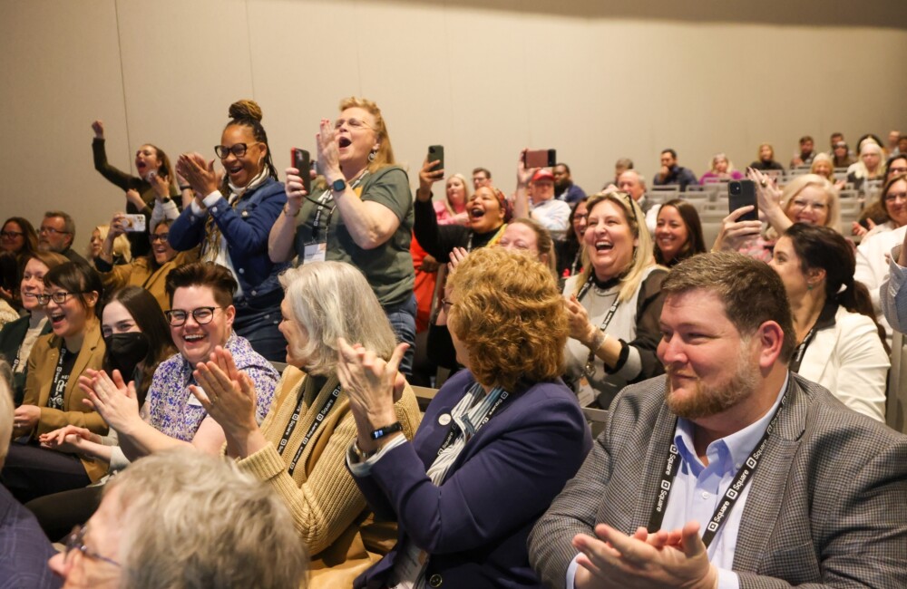 Conference attendees applaud enthusiastically.