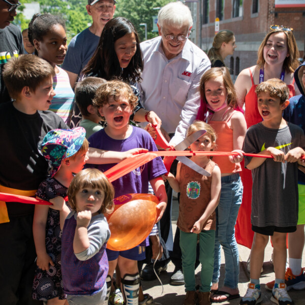 Children and adults participate in a ceremonial ribbon cutting.