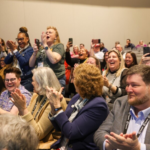 Conference attendees applaud enthusiastically.