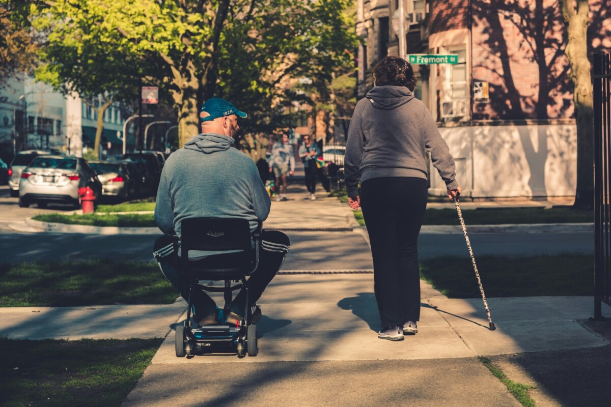 Una persona en silla de ruedas y otra con bastón caminan por una acera de Chicago, Illinois.