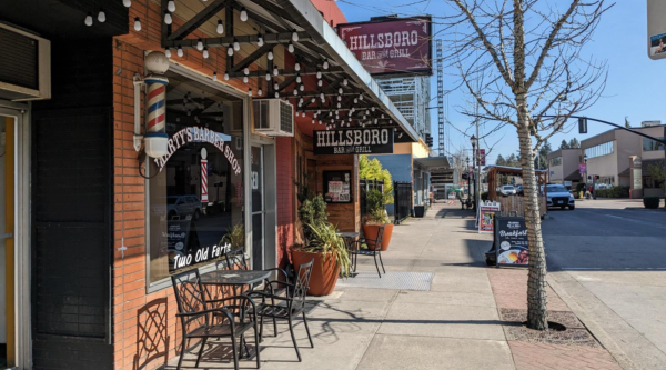 Vibrant storefronts and outdoor seating line a downtown street.