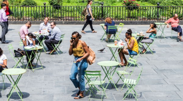 Gente sentada en las mesas de un patio al aire libre del centro