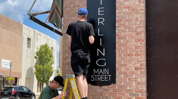 Installing a branded Main Street sign on a brick building in Sterling, Illinois