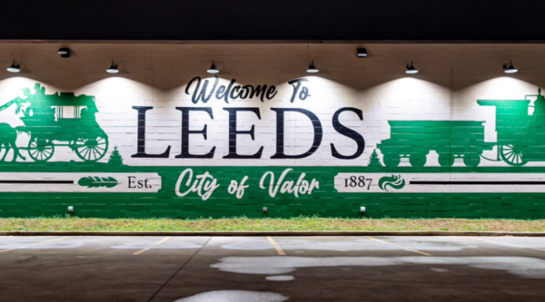 New mural in downtown Leeds showing horses and buggies and trains with the words "welcome to leeds"