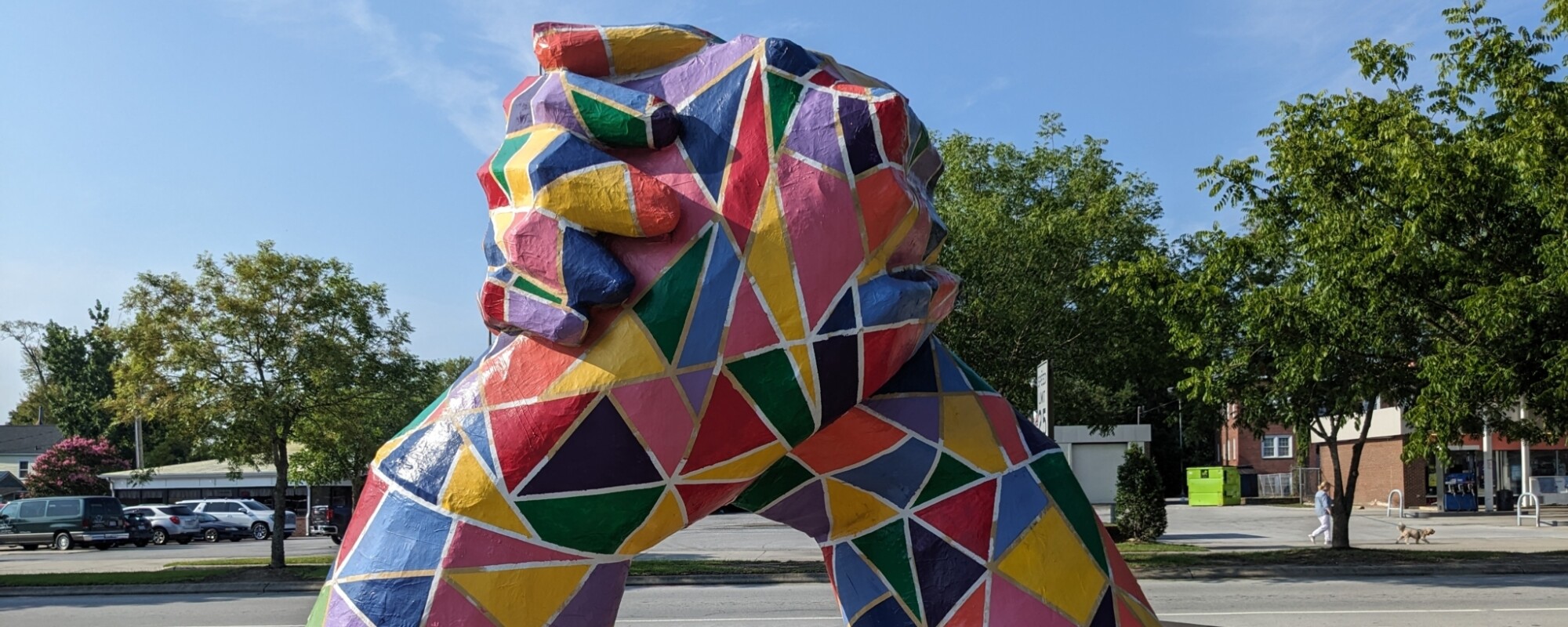 Gran escultura multicolor de manos que se levantan del suelo y se abrazan.