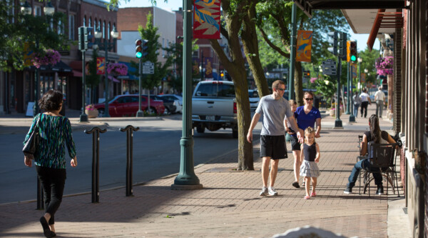 Young family walking down the sidewalk of a historic downtown street.
