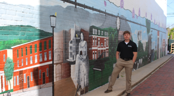 Todd Wolford poses next to the Edith Bolling Wilson timeline mural at the Heritage Walk in Downtown Wytheville.