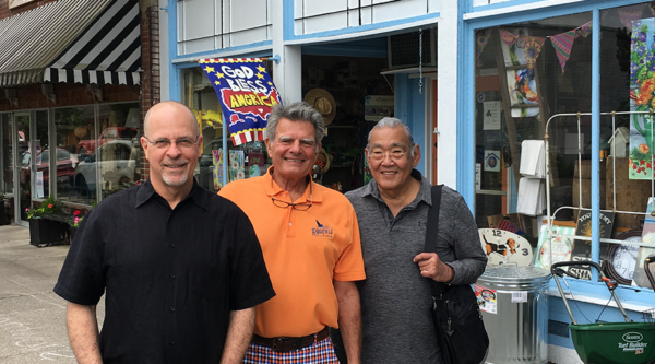 Group of men smile in front of small business
