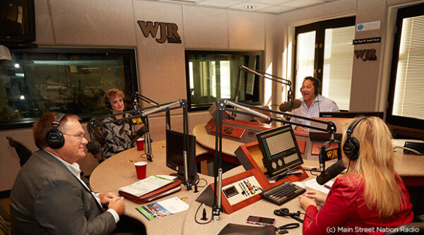 Grupo de cuatro personas sentadas en una cabina de grabación de podcasts