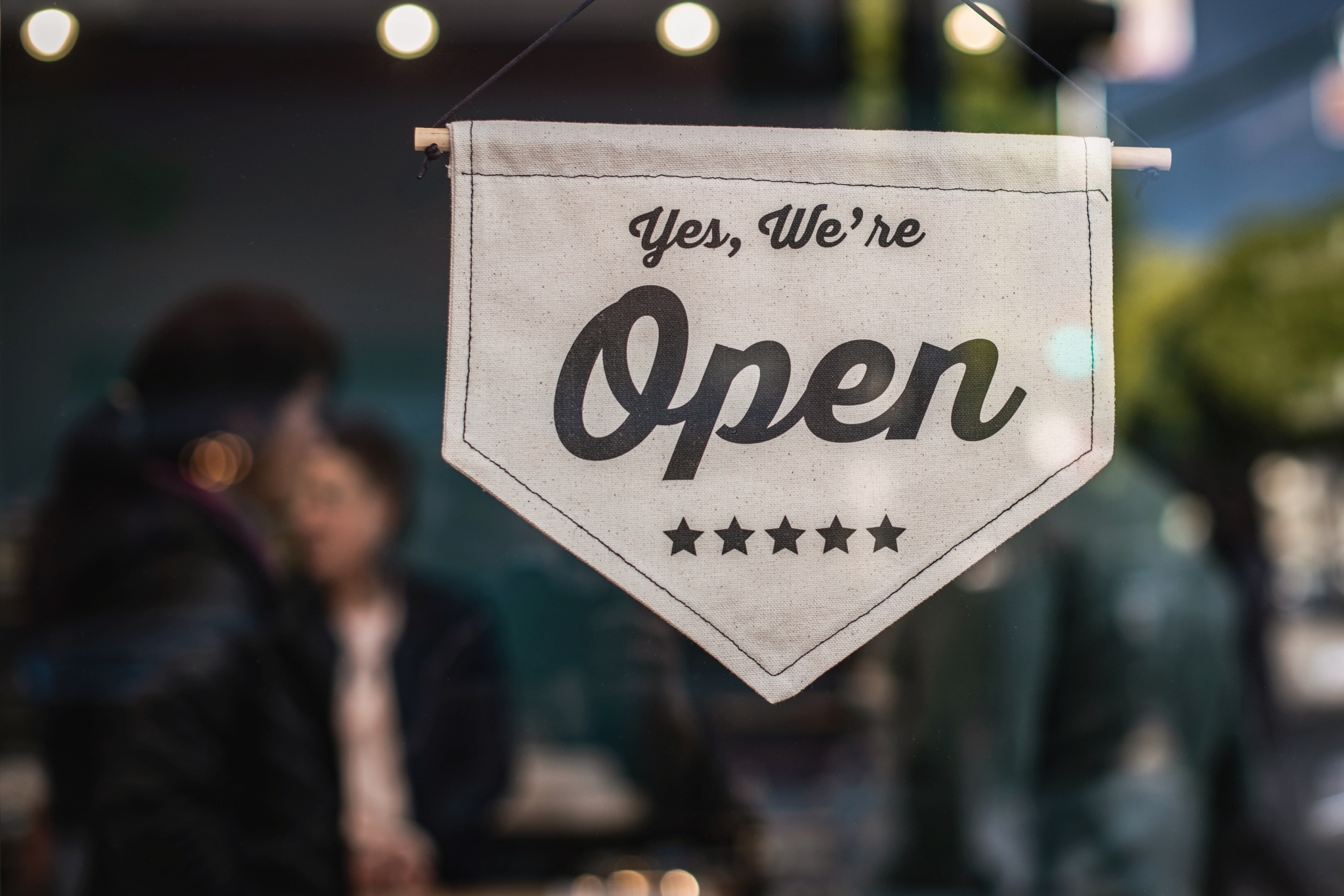 A sign reading, "Yes, we're open" hanging in a business window.