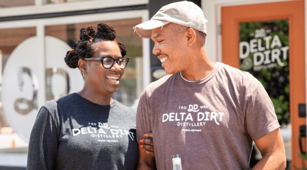 Un hombre y una mujer posan con una camiseta con el logo de delta dirt
