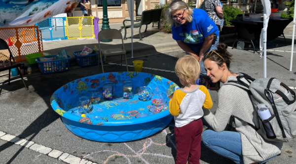 Un niño y dos mujeres miran en una piscina infantil en el Día de la Tierra de Hendersonville