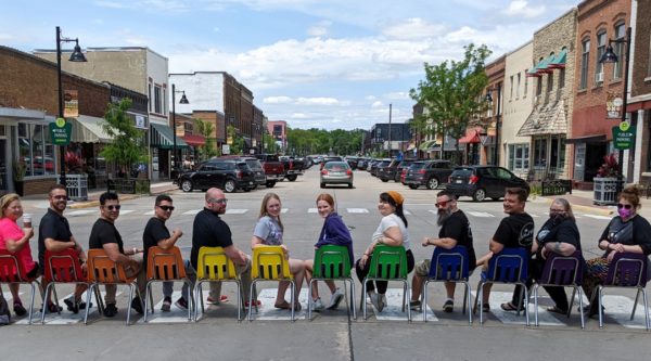 People sitting in a line of chairs making up the colors of the rainbow