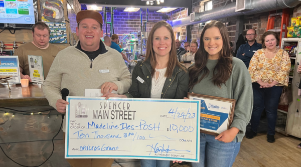 Three people pose with a large award check in a downtown restaurant