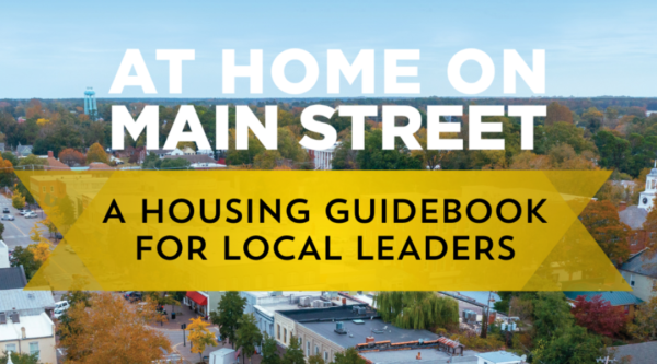 Portada de la guía de la vivienda con una foto aérea del centro de la ciudad y el texto "At Home on Main Street: Guía de la vivienda para dirigentes locales"