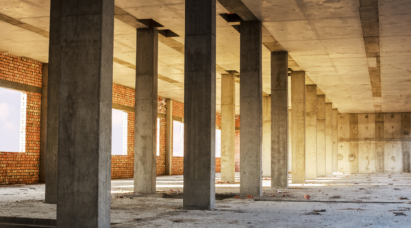 Interior vacío de un edificio en construcción con pilares de hormigón y suelos desnudos
