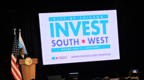Chicago mayor Lori Lightfoot stands next to a sign with the INVEST South/West logo
