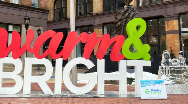 Large outdoor sign reading "warm and bright" next to an ice sculpture
