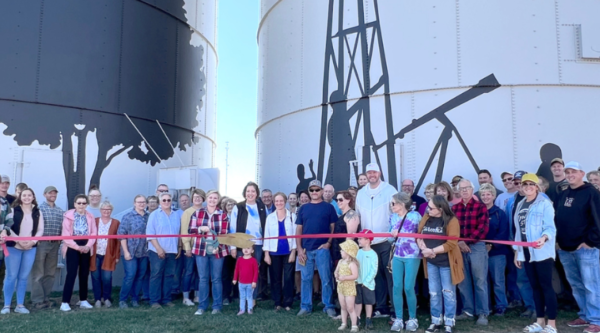 Ceremonia de inauguración de Naturally Iowa Grain Bin Gateway. La multitud posa para cortar la cinta delante de los silos.