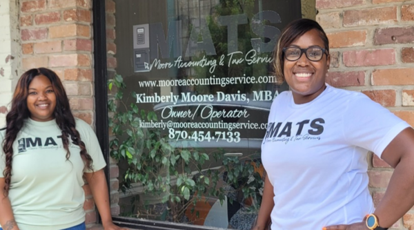 Two women standing in front of the storefront for Moore Accounting and Tax Service