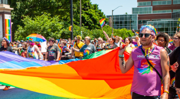 People holding a large pride flag during a parade