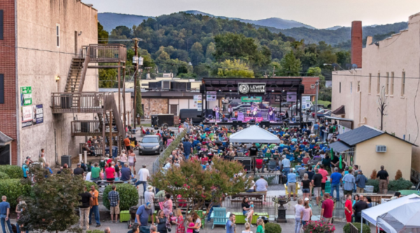 Large outdoor music performance on a historic Main Street with mountains in the background