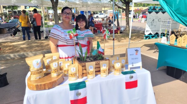 Una mujer y una niña con trajes tradicionales mexicanos venden mangos secos en un mercado al aire libre